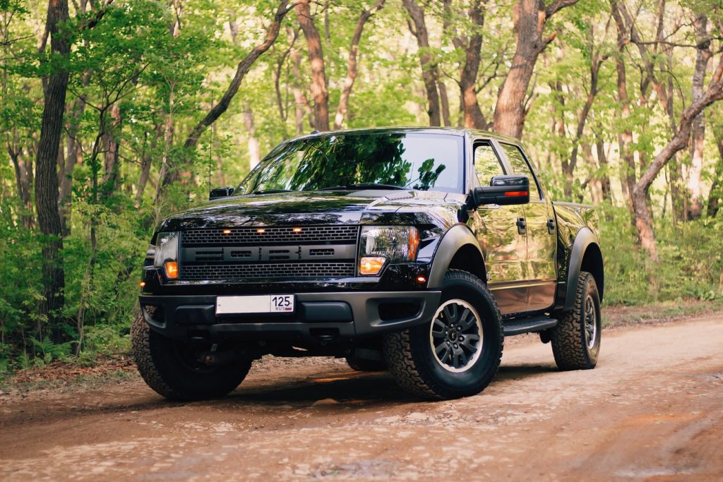 a ford raptor sitting on a back road